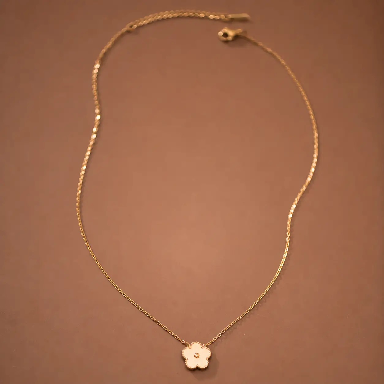 Delicate gold chain necklace with white flower pendant