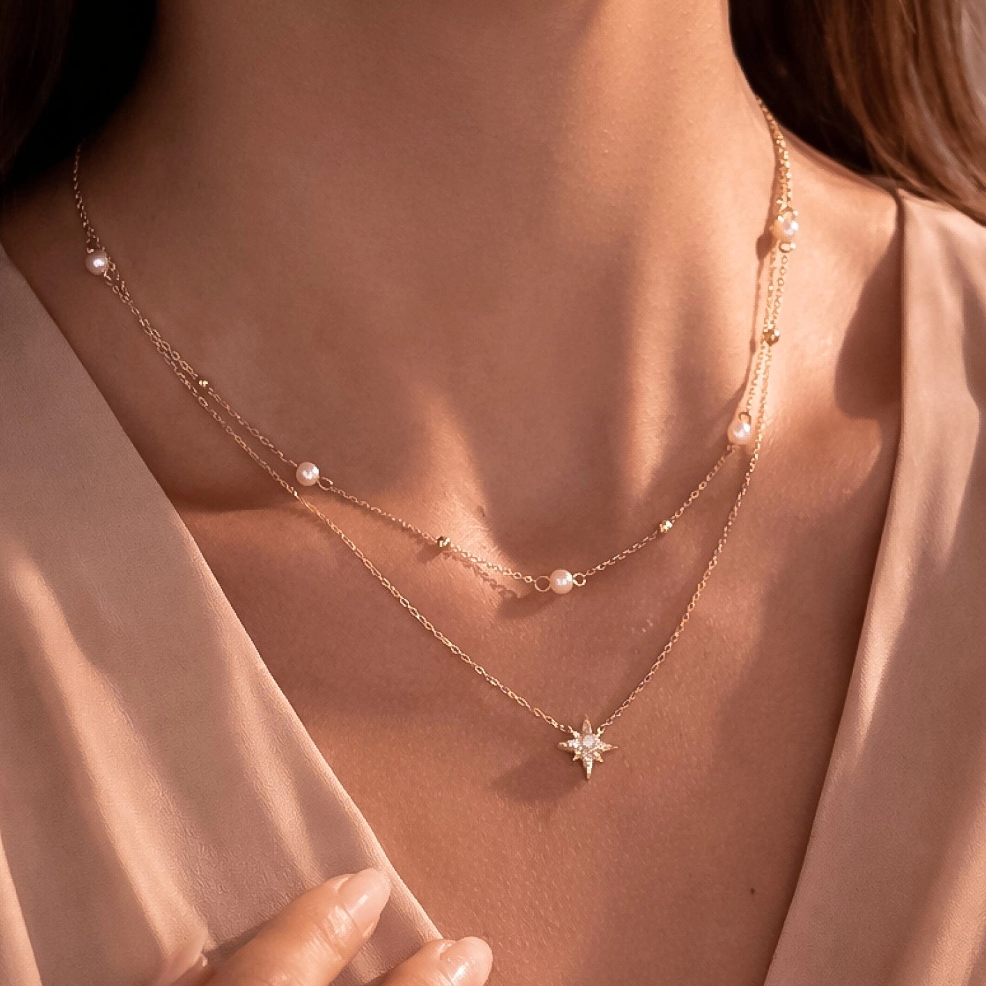 Layered gold chains with a pearl station strand and starburst pendant